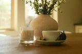 CHENDA STUDIO No. 03 Bergamot Noir candle styled beside a ceramic cup, figs and greenery